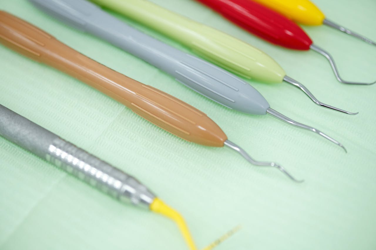 Close-up of various colorful dental tools on a light green background, ideal for dental care visuals.