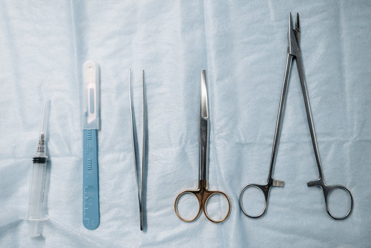 services-07 Flat lay of surgical tools including scissors, forceps, and syringe on a sterile blue cloth.