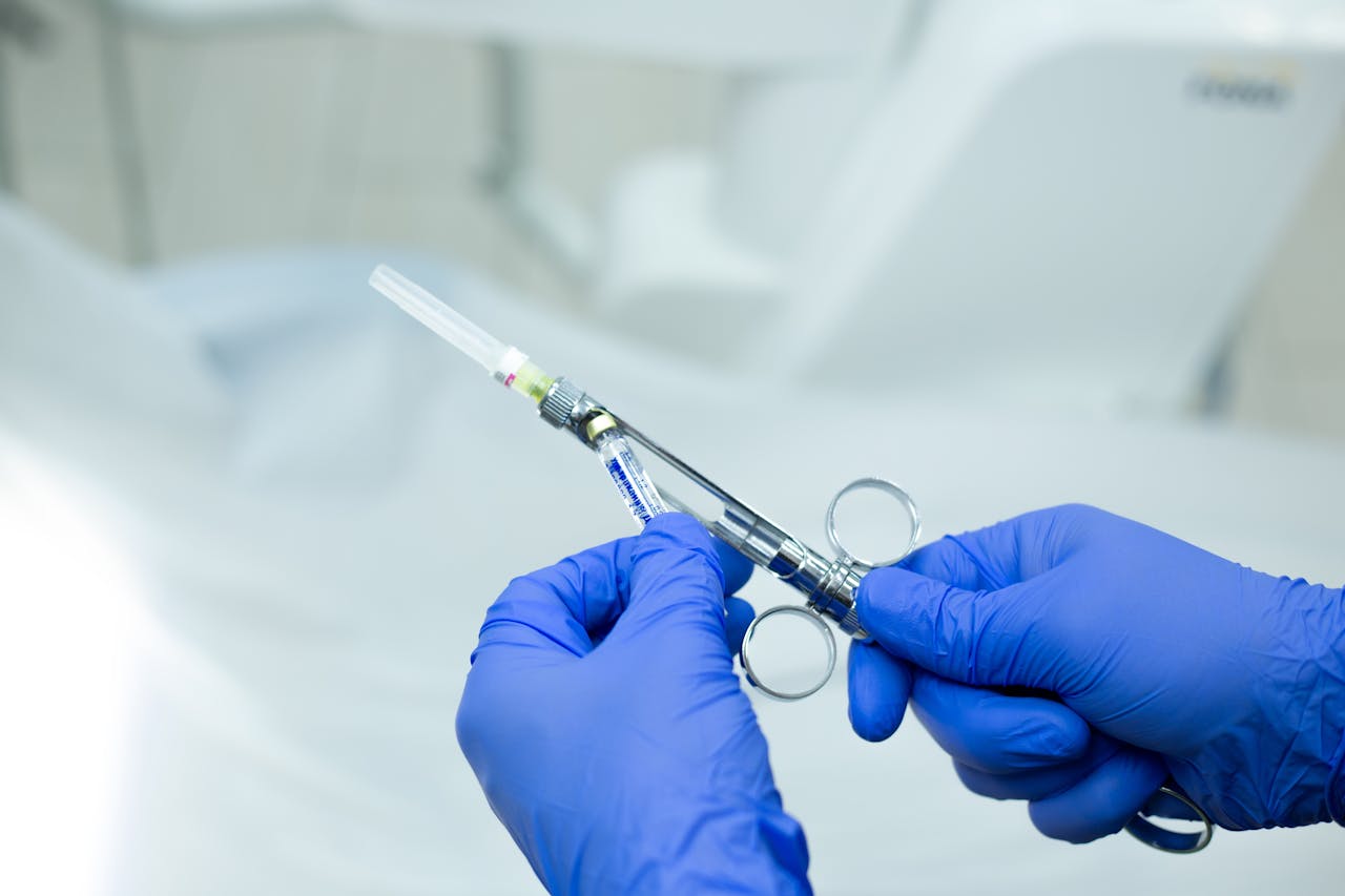 portfolio-01 A close-up of gloved hands holding a sterile medical syringe in a healthcare setting.